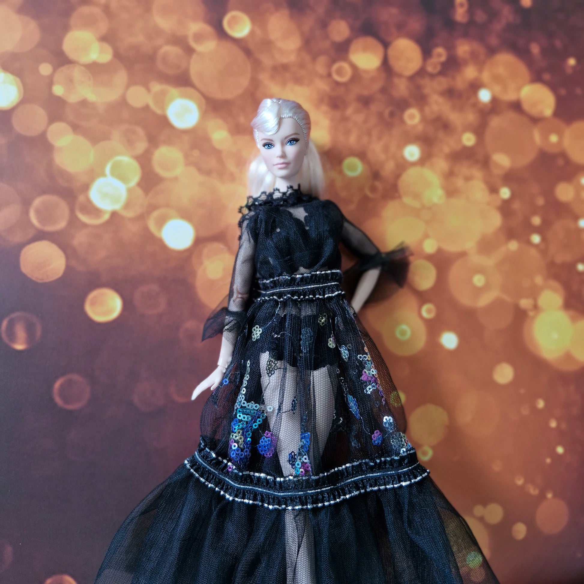 Blonde Barbie doll wearing black sheer lace and sequin detailed gown, elegant stance.