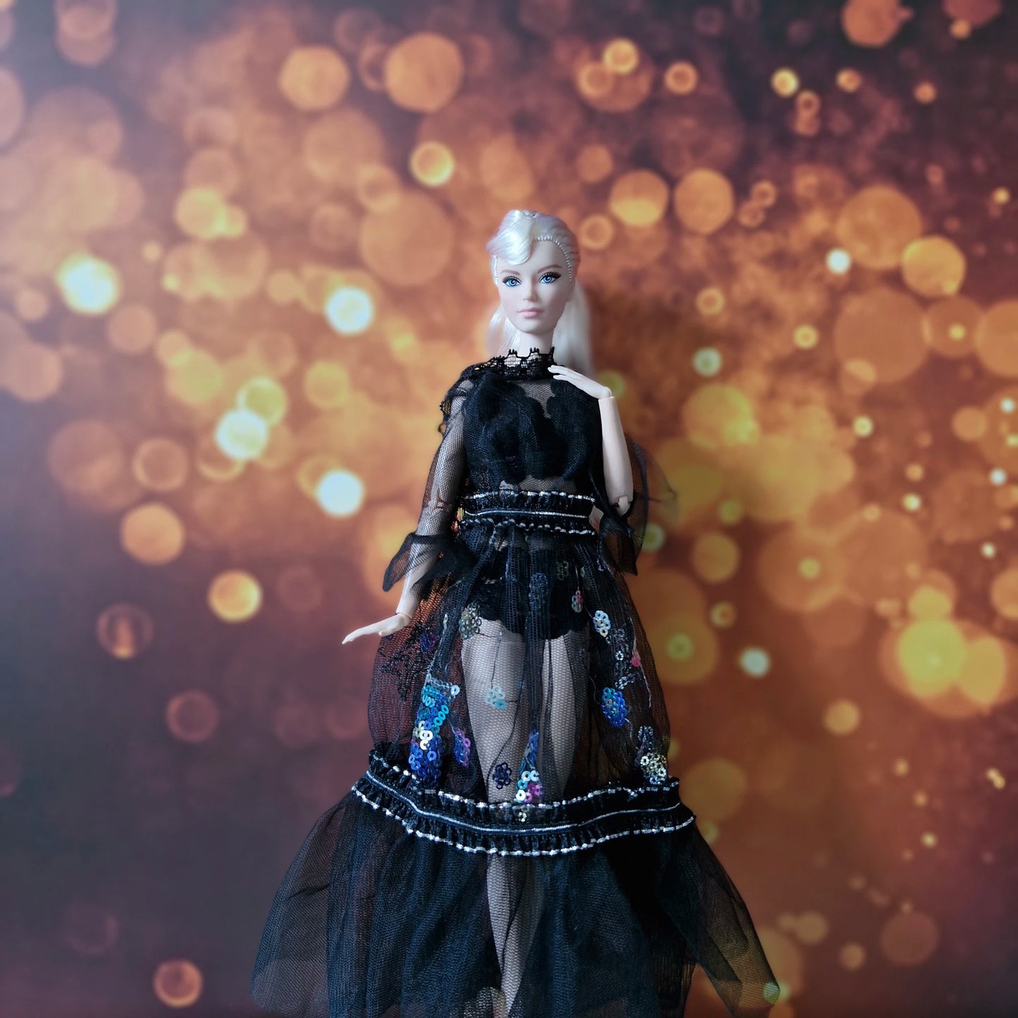 Blonde Barbie doll in elegant black sheer robe with colorful sequin embellishments over lingerie.