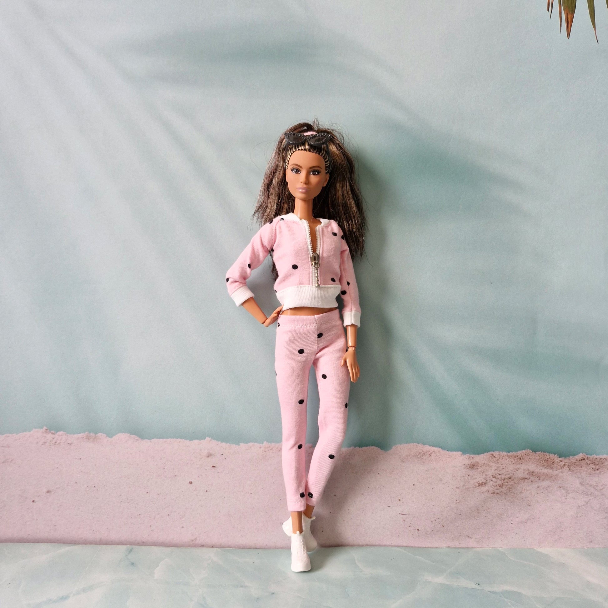 Front view of Barbie doll in pink polka dot zip-up tracksuit, hand on hip.