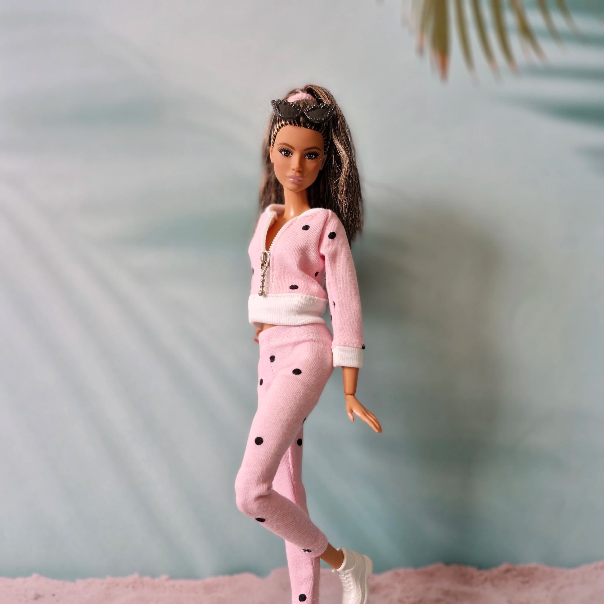 Barbie doll in pink polka dot tracksuit with sunglasses on head, side pose.