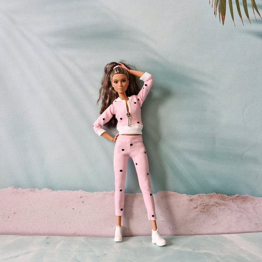 Barbie doll in pink polka dot athleisure tracksuit, stylish pose with hand on head.