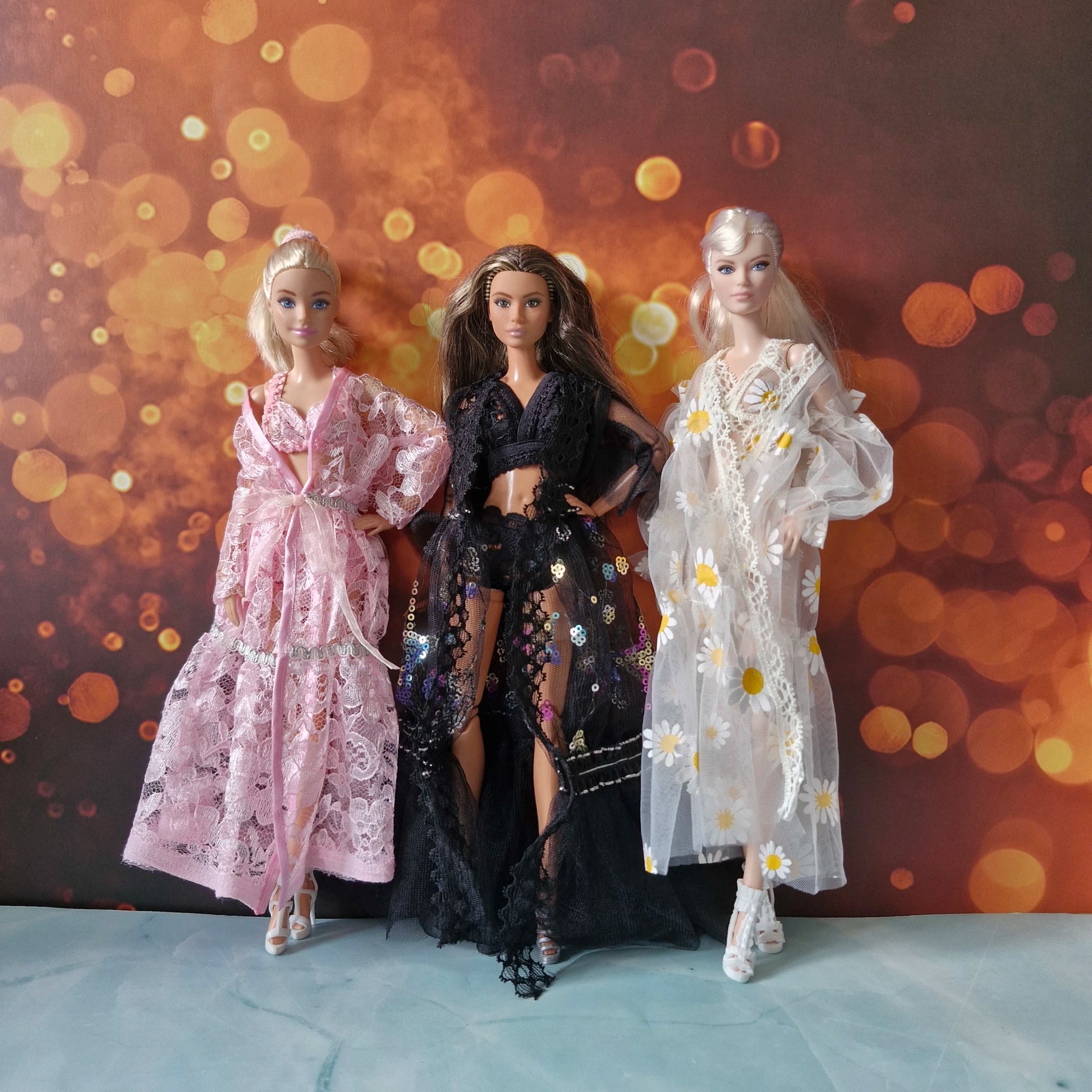 Elegant Barbie lingerie robe set of 3 styles (pink, black, daisy) against bokeh background.