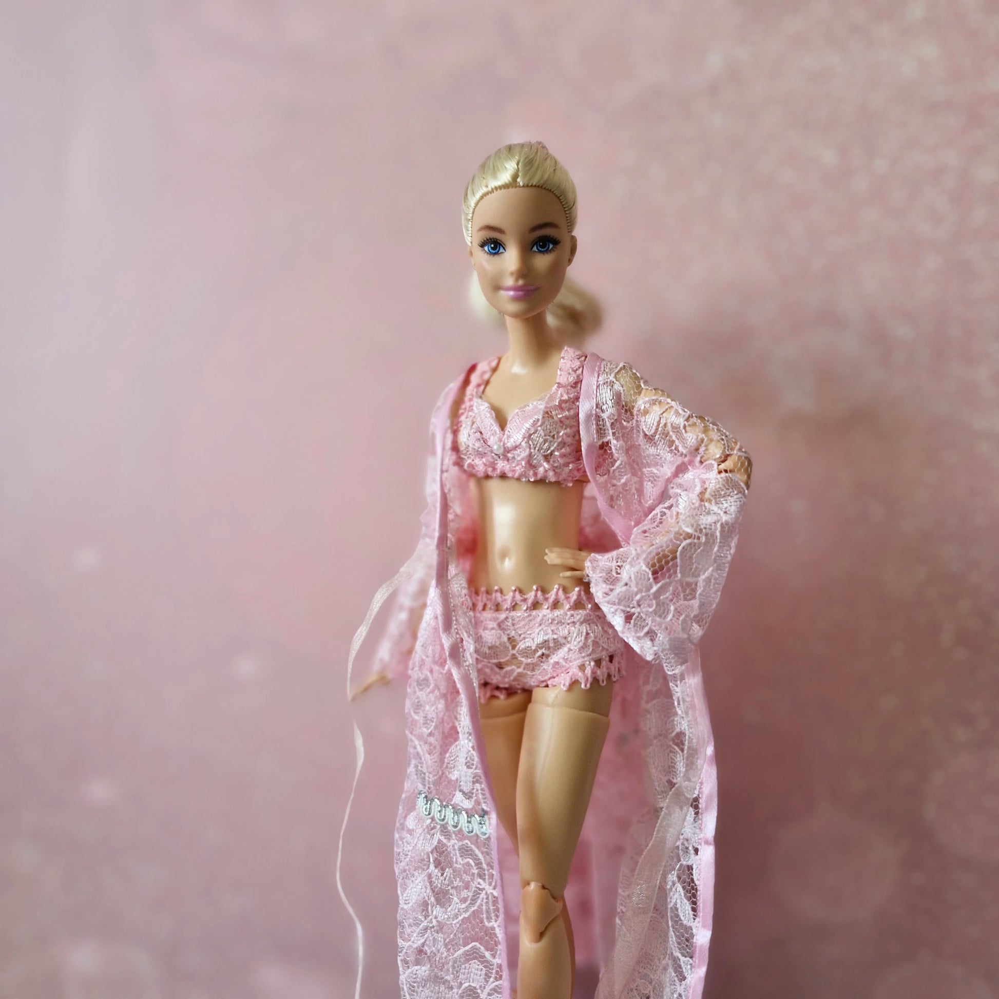 Blonde Barbie doll models elegant pink lace robe and lingerie, part of 3-set collection.