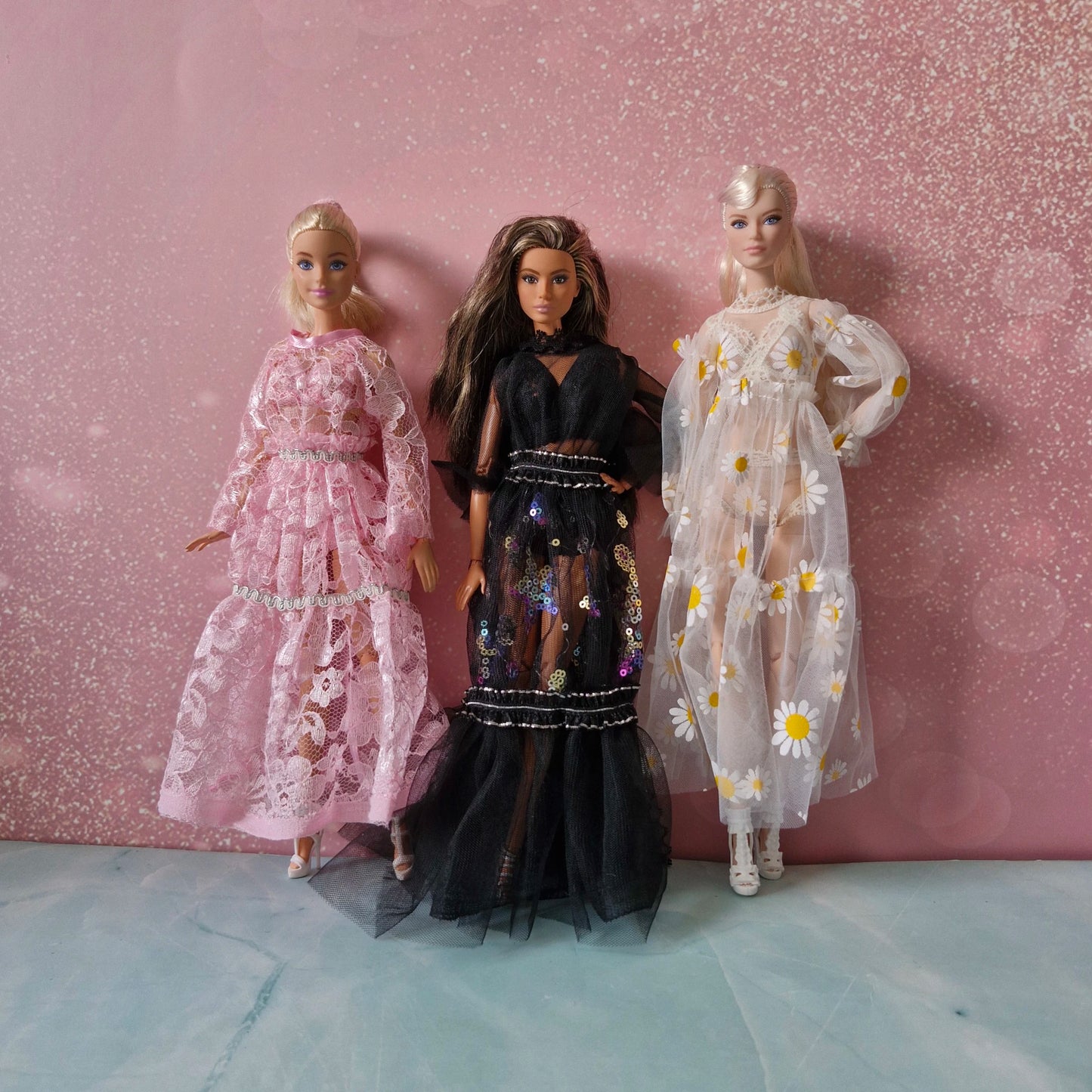 Three Barbie dolls showcasing the luxurious lingerie robe collection: pink, black, and daisy styles.