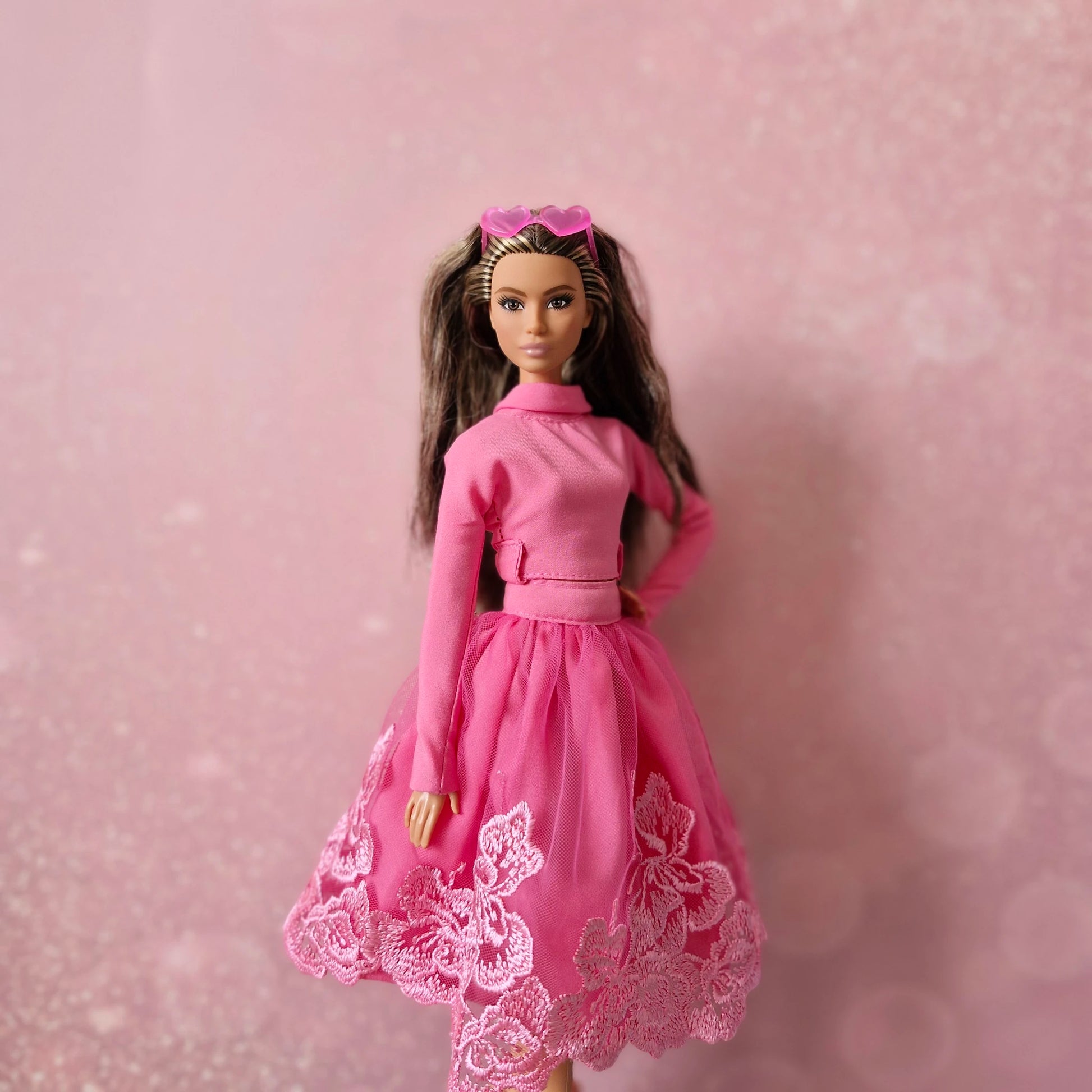 Brunette Barbie doll in pink mock neck top, lace tulle skirt, and pink heart sunglasses.
