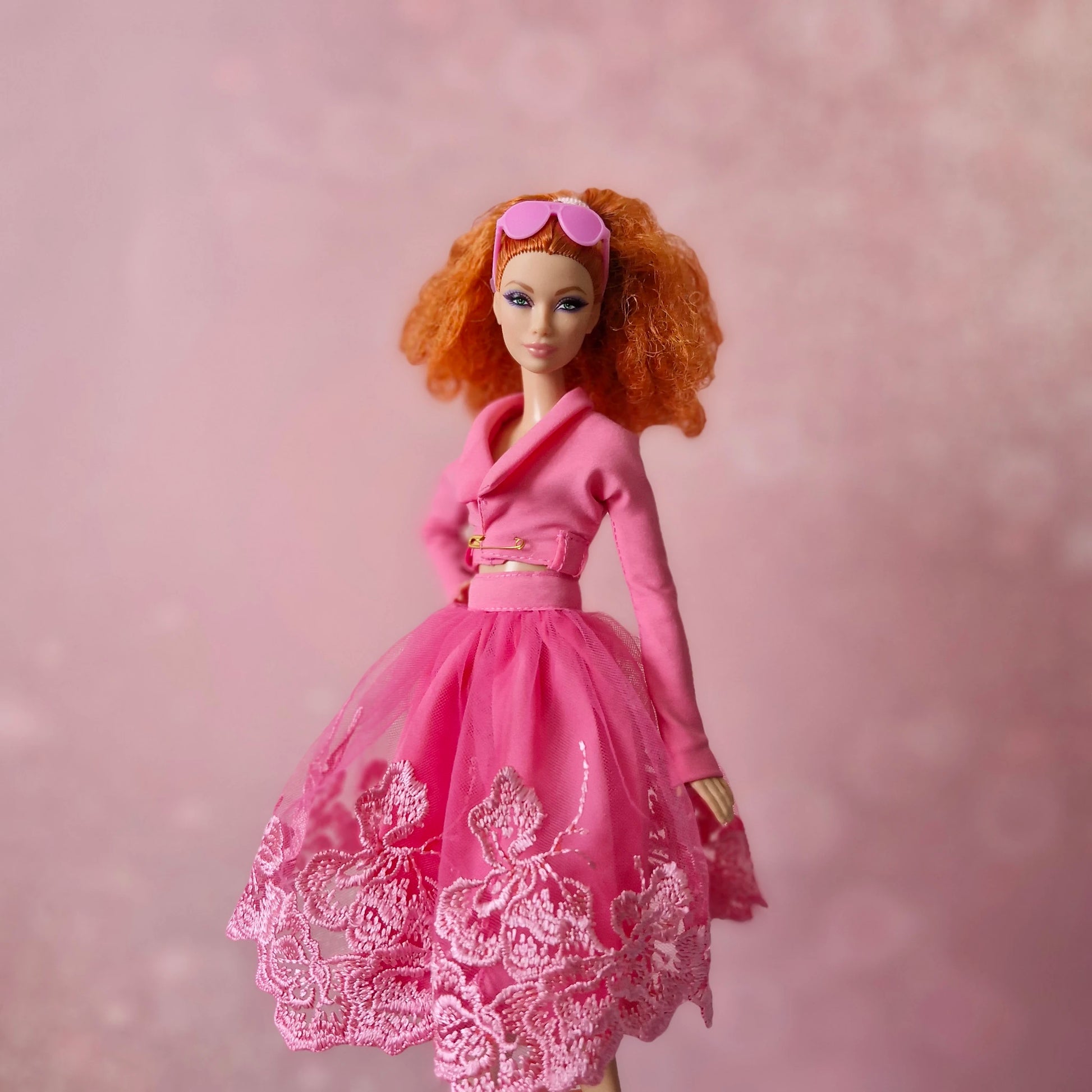 Red-haired Barbie doll, side view in pink cropped jacket and lace tulle skirt.