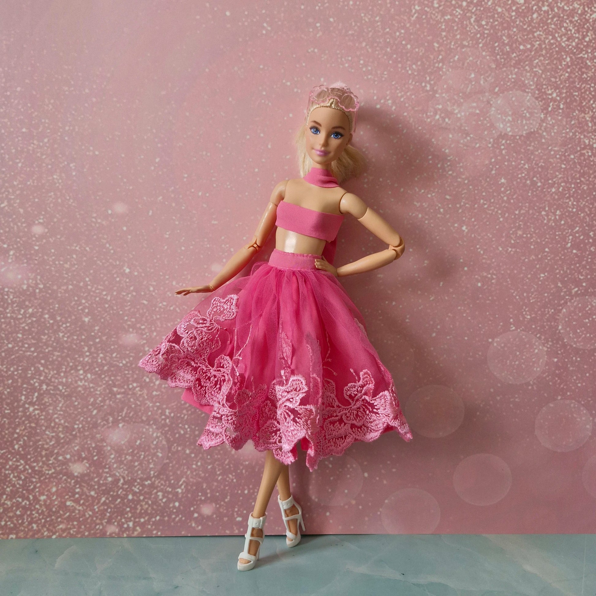 Blonde Barbie doll in pink bandeau top and lace tulle skirt with white heels, full view.