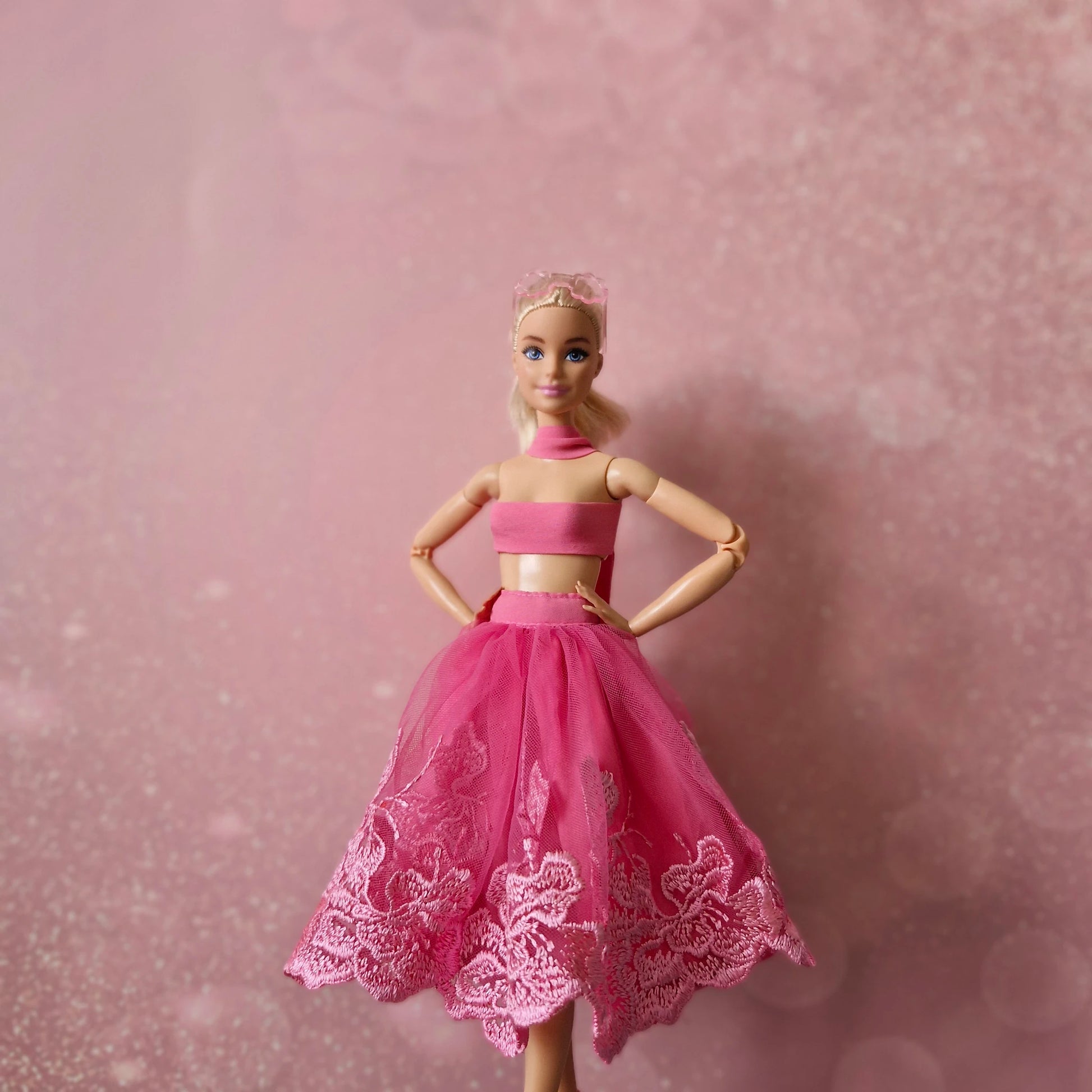 Blonde Barbie doll posing confidently in pink bandeau top and lace tulle skirt.