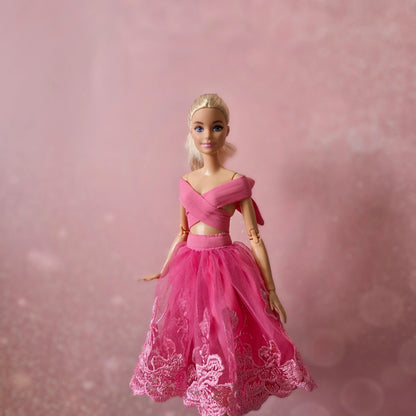 Blonde Barbie doll in pink criss-cross wrap top and pink lace tulle skirt, elegant pose.