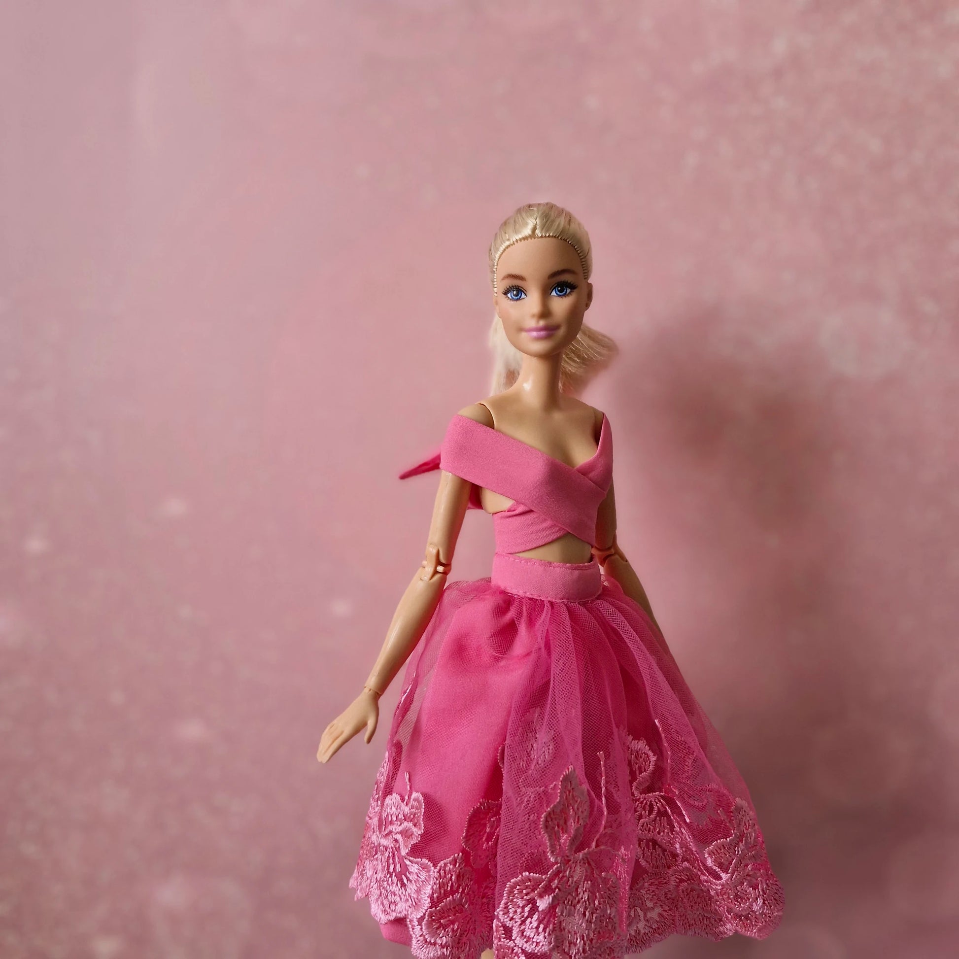 Blonde Barbie doll, close-up in pink criss-cross wrap top and lace tulle skirt.