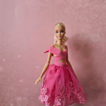 Blonde Barbie doll, close-up in pink criss-cross wrap top and lace tulle skirt.