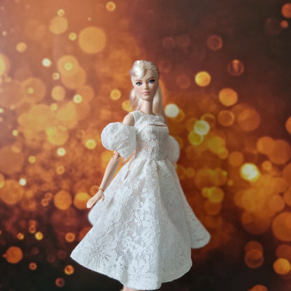 Blonde Barbie doll in elegant white lace dress with puff sleeves, gentle movement.