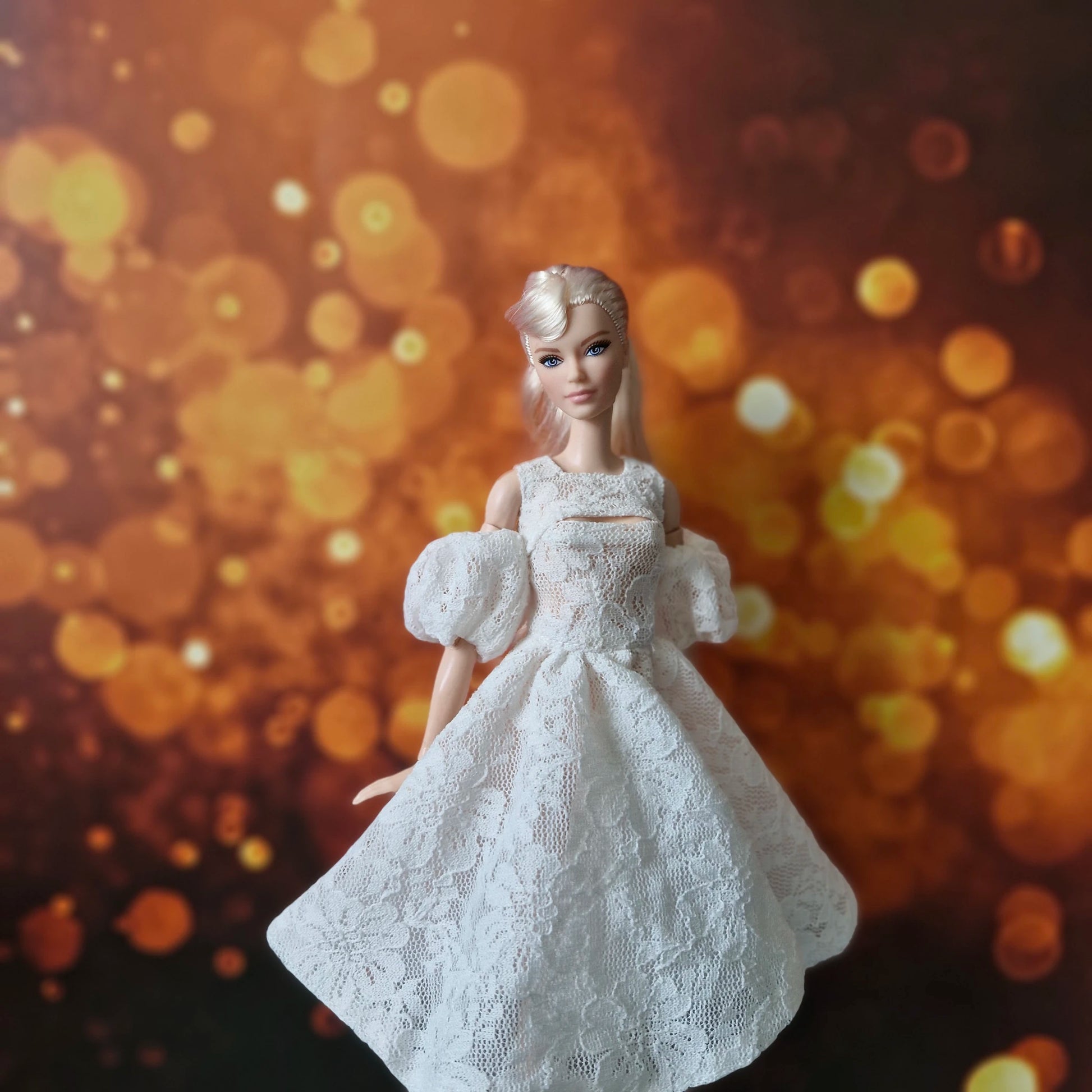 Blonde Barbie doll elegant in white lace dress with puff sleeves and cut-out detail.