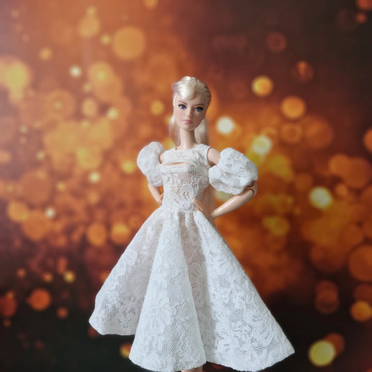 Front view of blonde Barbie doll wearing white lace party dress with puff sleeves and cut-out.