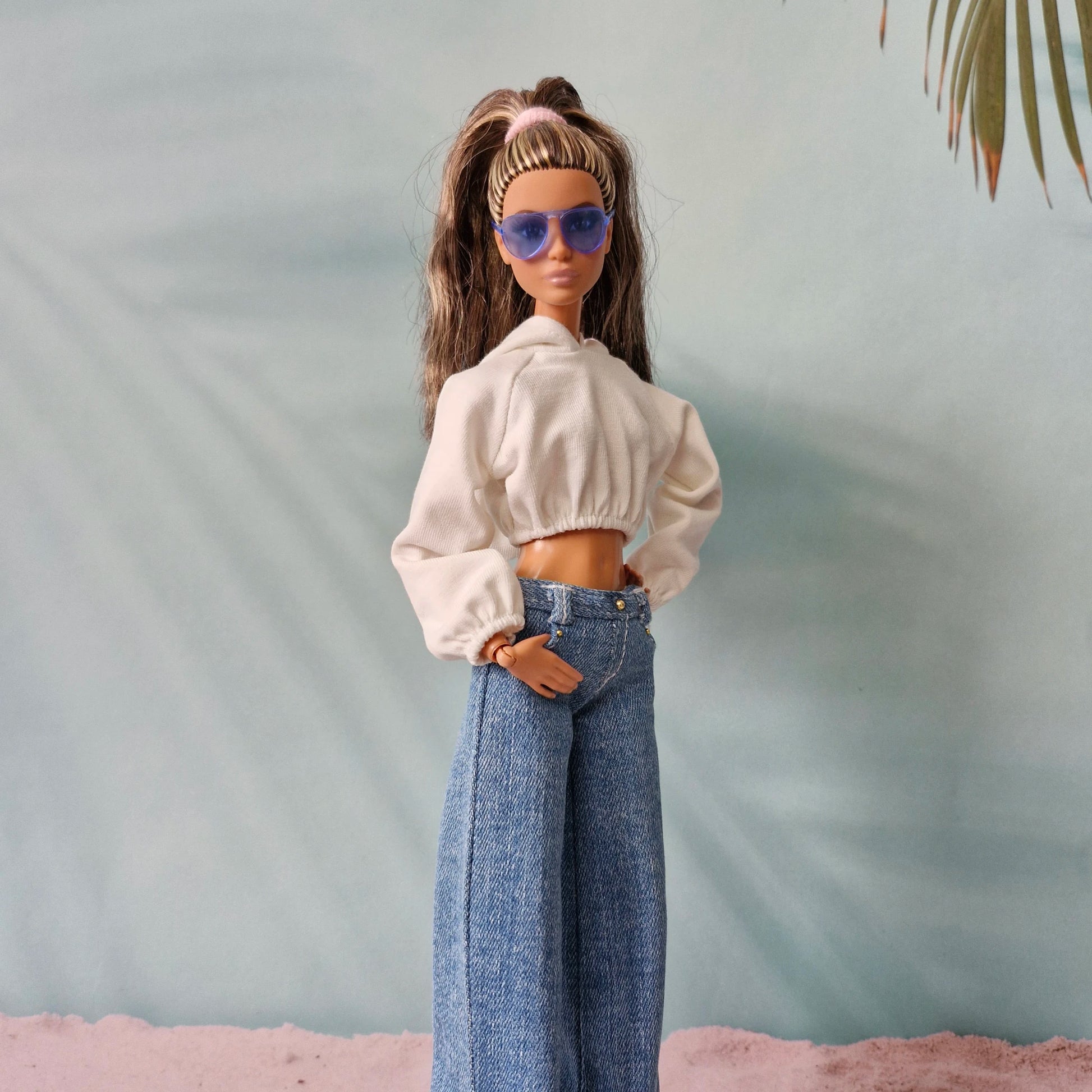 Barbie doll in white cropped hoodie and dark wash wide-leg denim jeans, blue sunglasses.