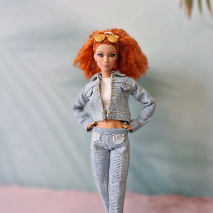 Barbie doll with red hair in full light wash denim outfit with white crop top and sunglasses.