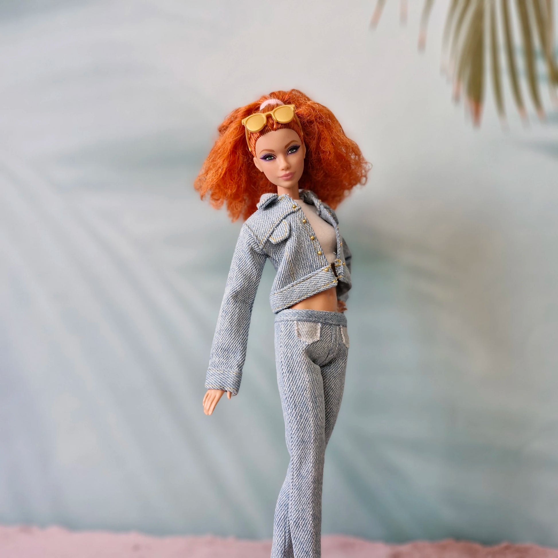 Barbie doll with red hair in light wash denim jacket and jeans set, orange sunglasses.