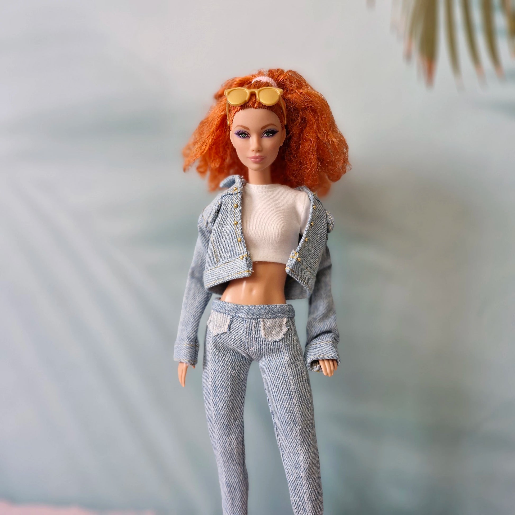 Barbie doll models light wash denim jacket over white crop top and matching jeans.