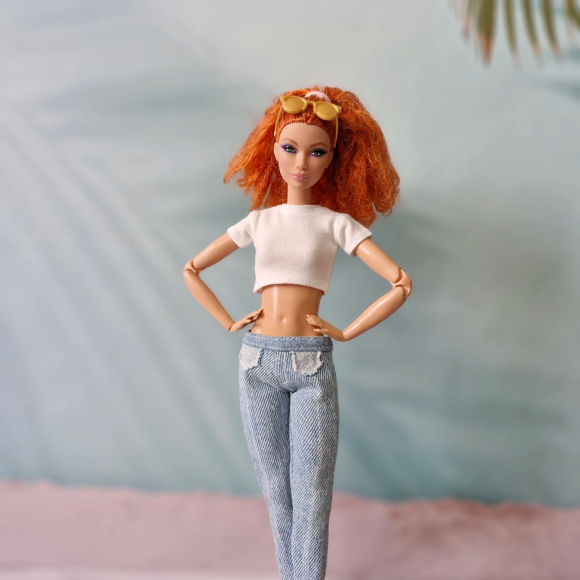 Barbie doll with red hair wearing white crop top and light wash denim jeans.