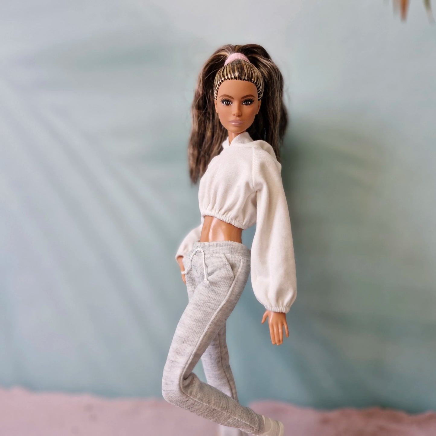 Barbie doll in white cropped hoodie and grey sweatpants athleisure outfit - side view.