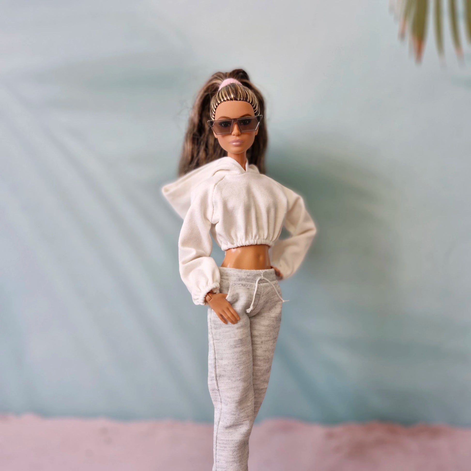 Stylish Barbie doll in white hoodie, grey sweatpants, and sunglasses - athleisure look.
