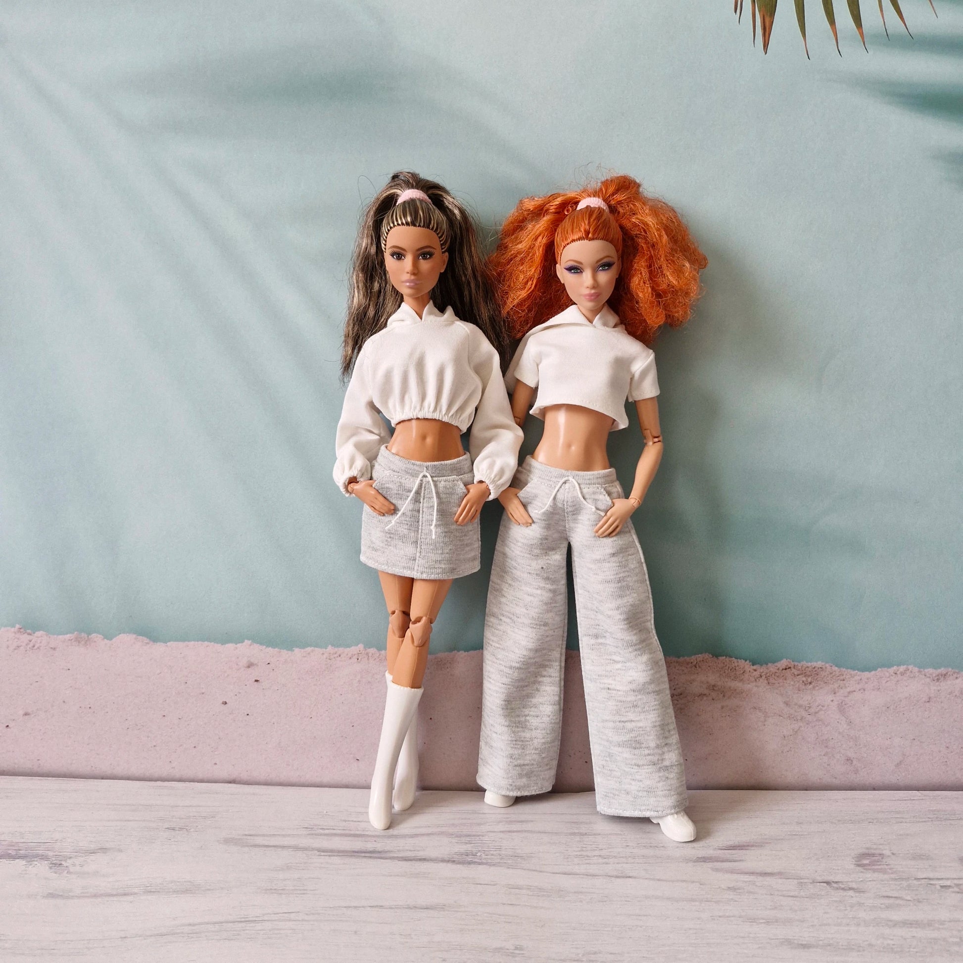 Two Barbie dolls in mix-and-match white and grey athleisure outfits - skirt and wide pants.