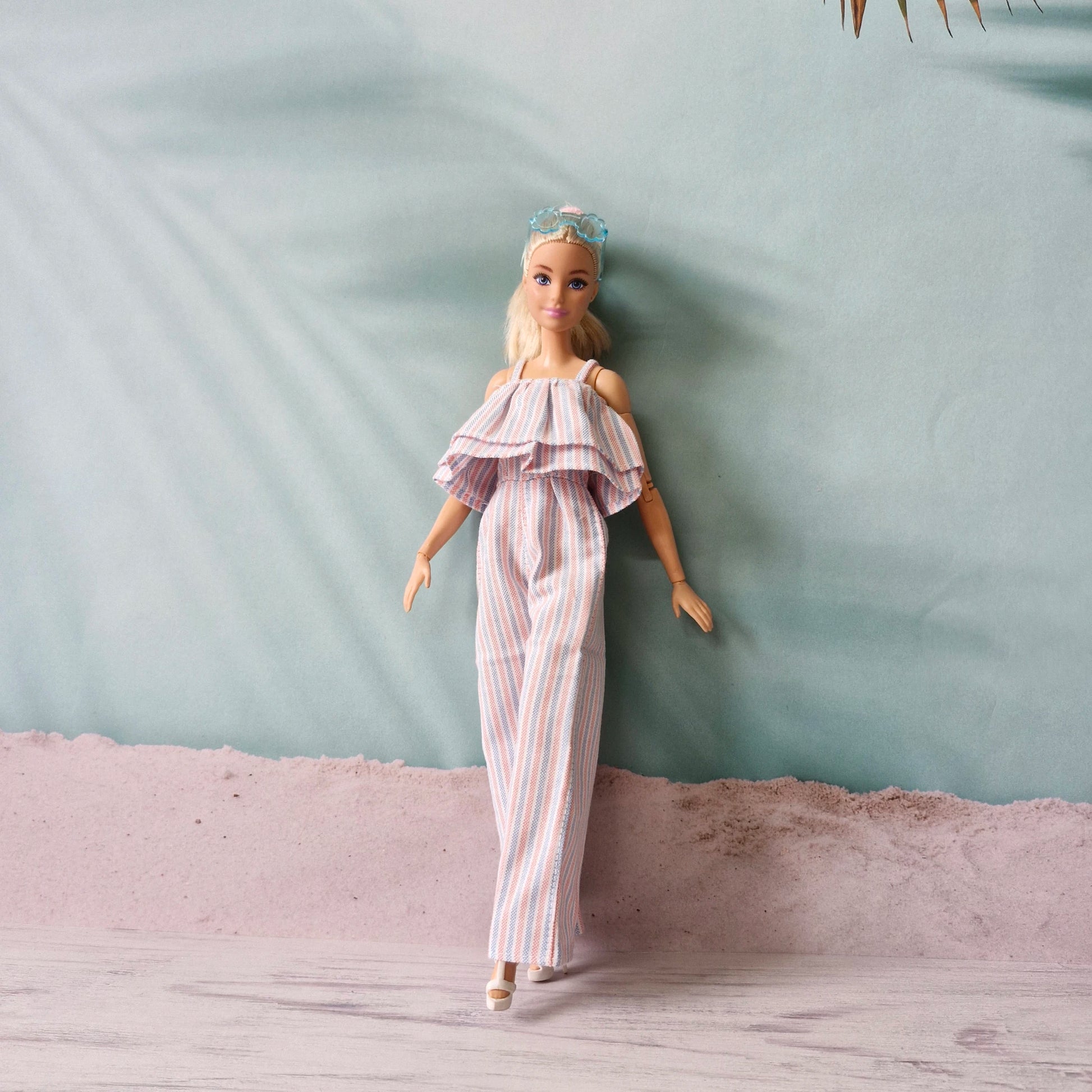 Barbie doll walking in stylish striped wide-leg jumpsuit with off-shoulder ruffle.