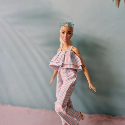 Barbie doll in motion wearing summer striped ruffle jumpsuit and blue sunglasses.