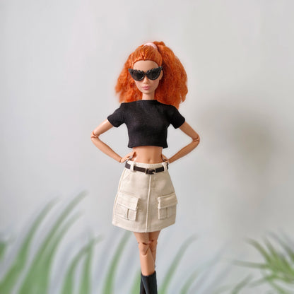 Fashion Barbie doll with red hair wearing a black top, white belted cargo skirt, and sunglasses, showing off her modern style.