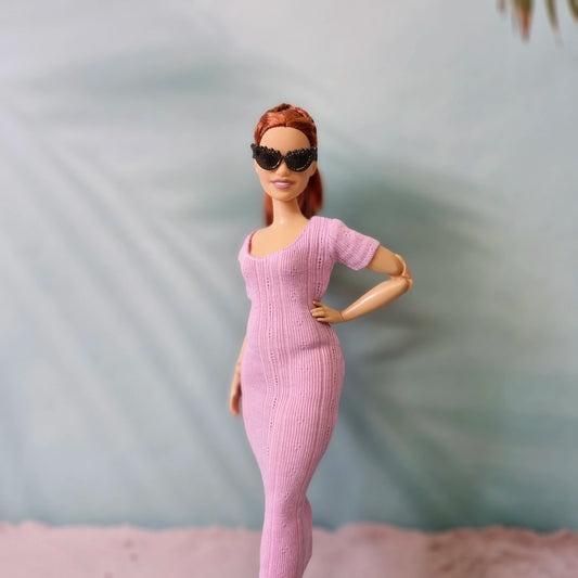 Barbie doll wearing black sunglasses with a pink ribbed midi dress, one hand on hip.