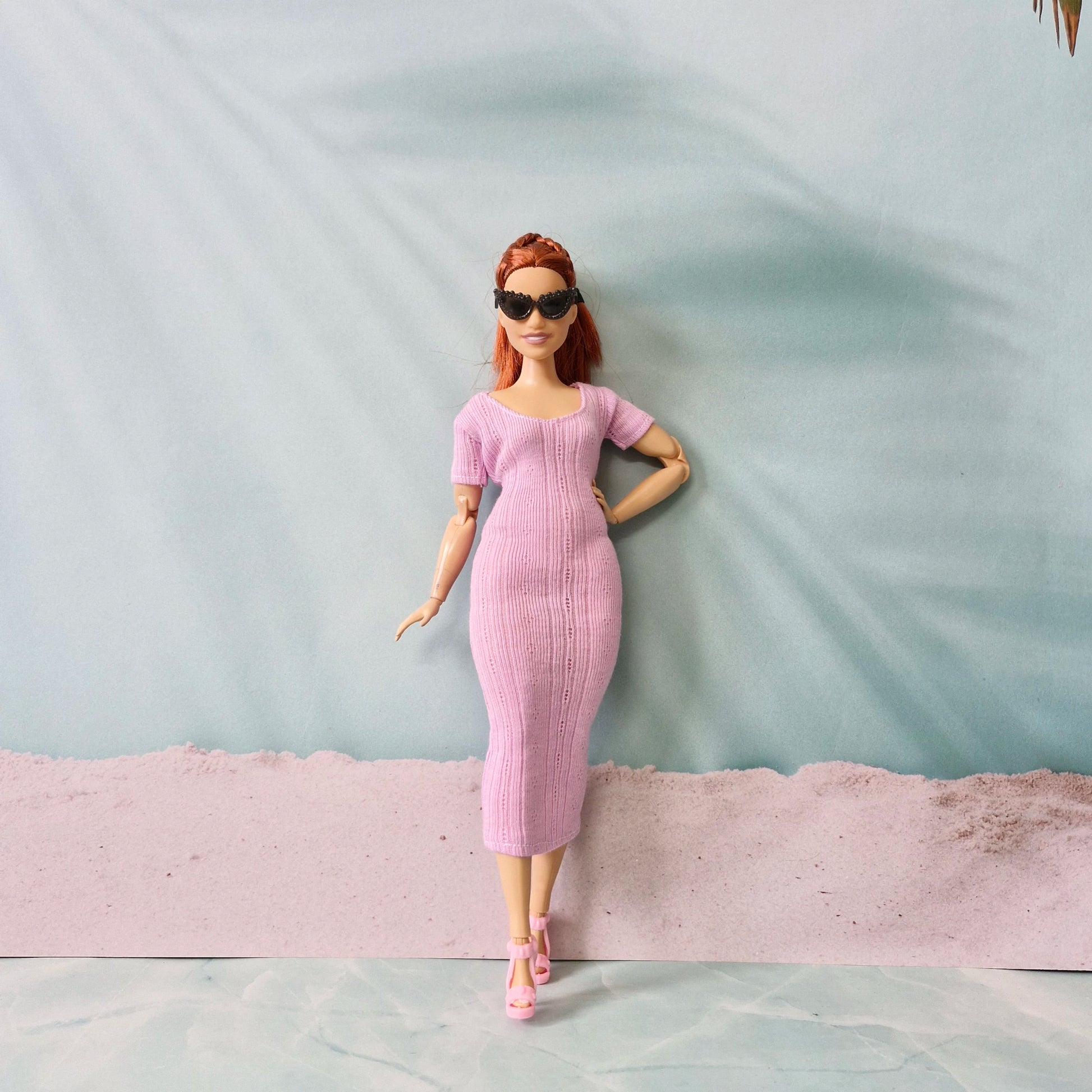 Full-length view of Barbie doll in pink midi dress and pink heels, wearing black sunglasses.