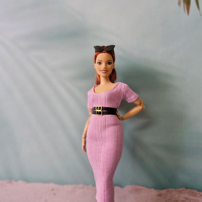 Barbie doll models pink ribbed midi dress accessorized with a wide black belt and sunglasses on head.