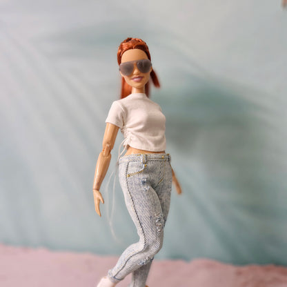 Curvy Barbie doll in a dynamic pose showing off the side-tie detail on her white t-shirt and the fit of the distressed jeans.