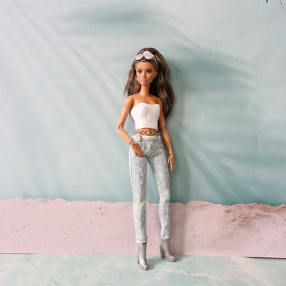 Full-length view of a brunette Barbie doll in a white tube top, distressed jeans, and silver boots, standing confidently.