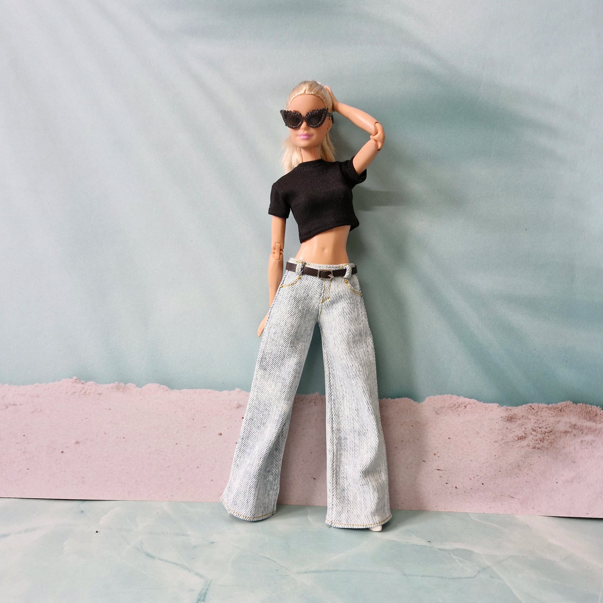 Blonde Barbie doll posing in light wash wide-leg jeans and a black crop top.