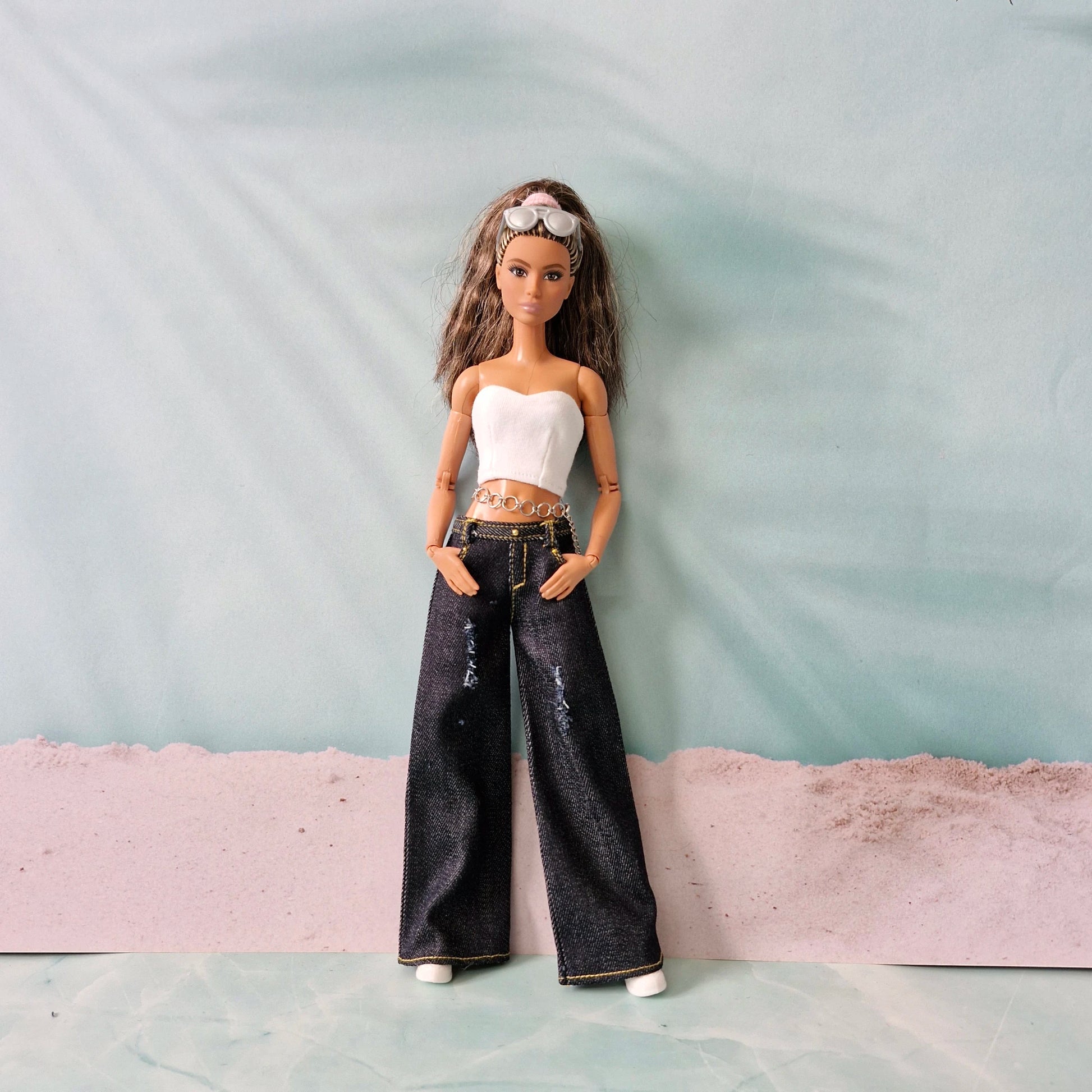 Barbie doll modeling dark wash wide-leg jeans with a white tube top and chain belt.