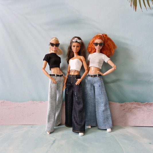 Three Barbie dolls modeling different wide-leg jeans outfits: light blue, dark denim, and light wash.