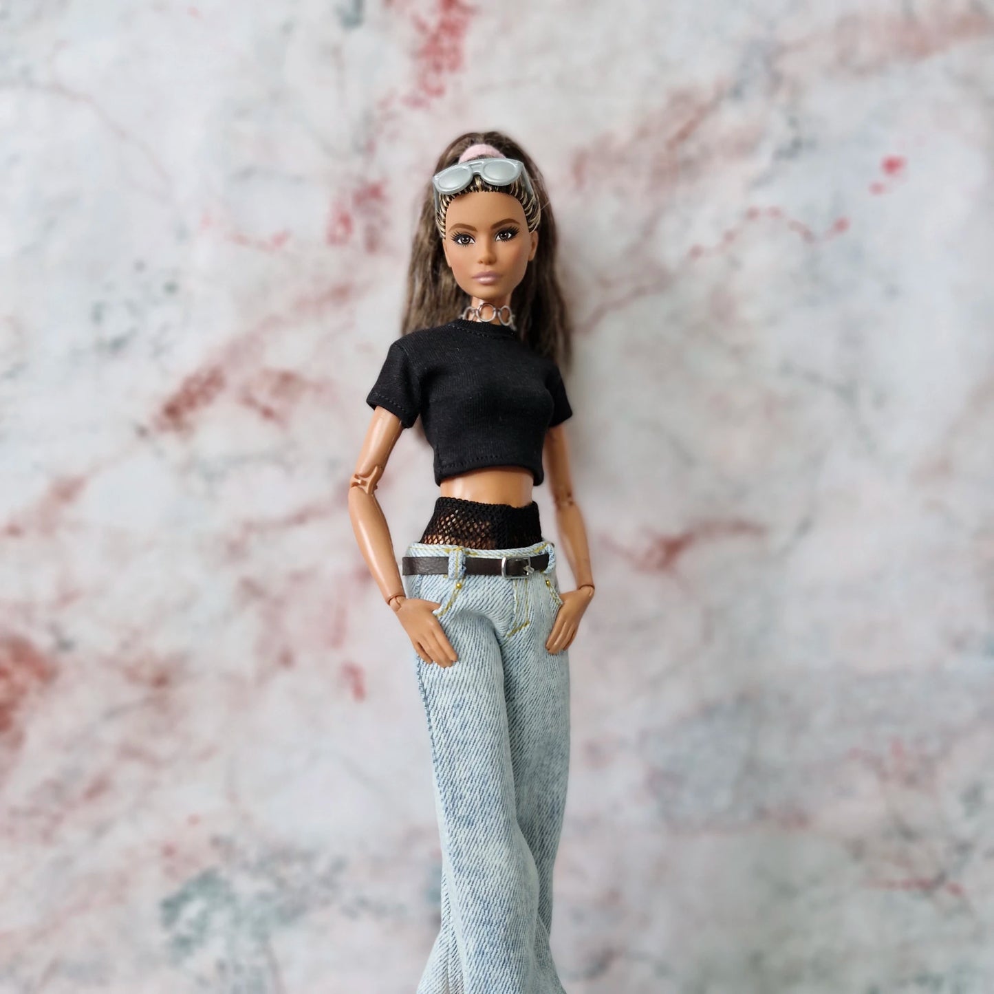 Barbie doll with hands in pockets, modeling Y2K outfit with layered crop top and light-wash wide-leg jeans.