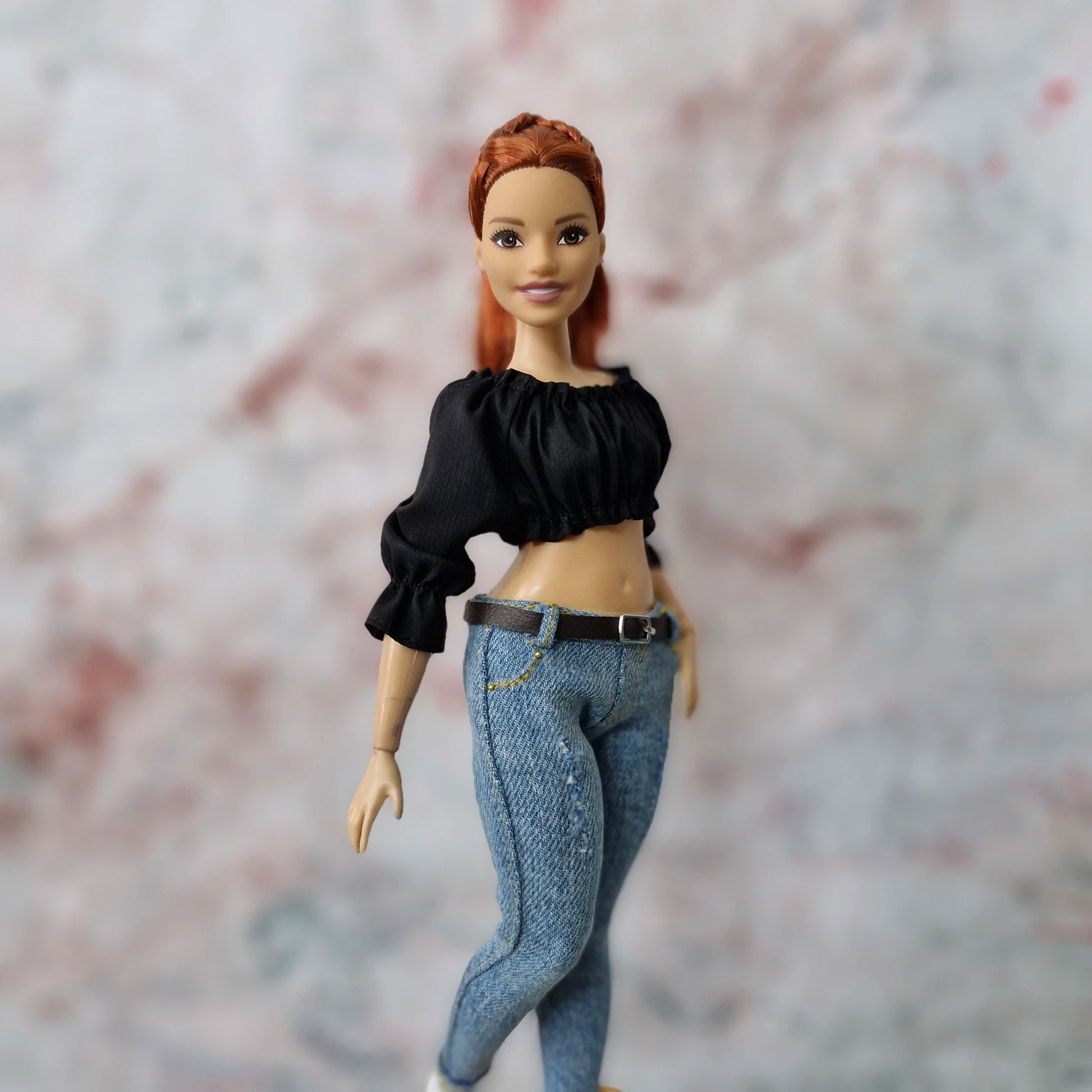 Close-up of Curvy Barbie doll in black off-shoulder top and belted skinny jeans.