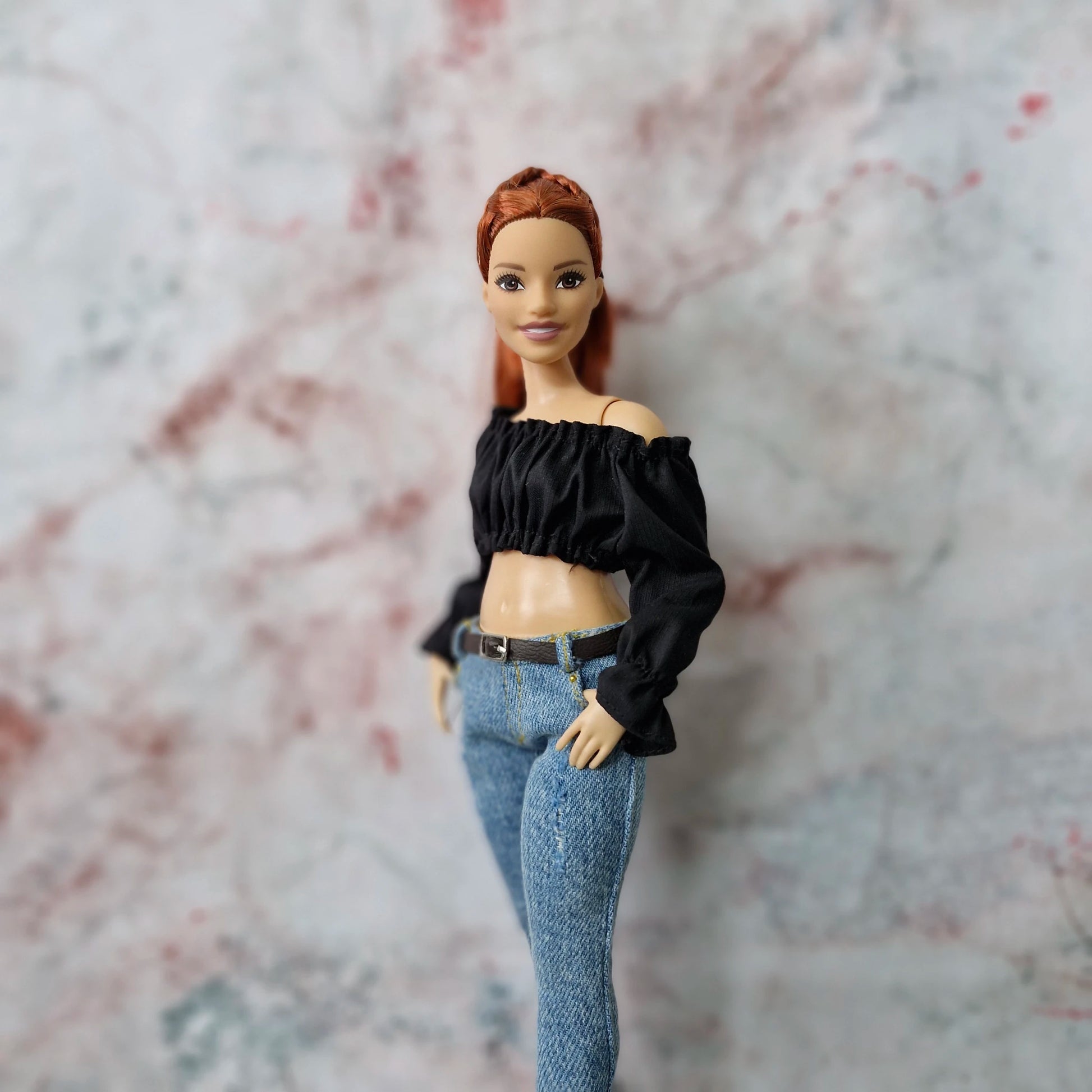 Side view of Curvy Barbie doll wearing black off-shoulder crop top and skinny jeans.