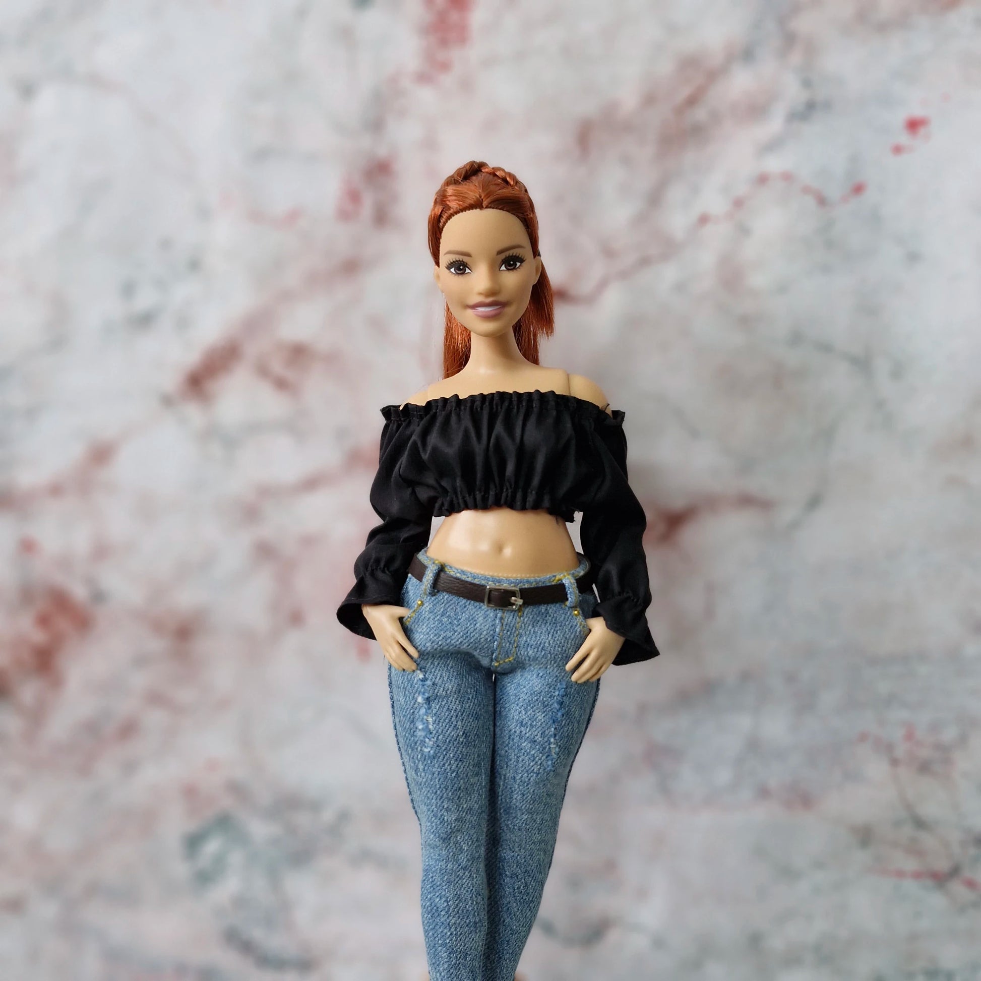 Red-haired Curvy Barbie doll in black off-shoulder crop top and jeans, with hands in pockets.