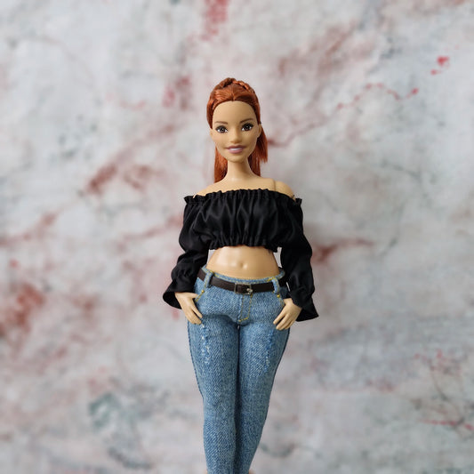 Red-haired Curvy Barbie doll in black off-shoulder crop top and jeans, with hands in pockets.