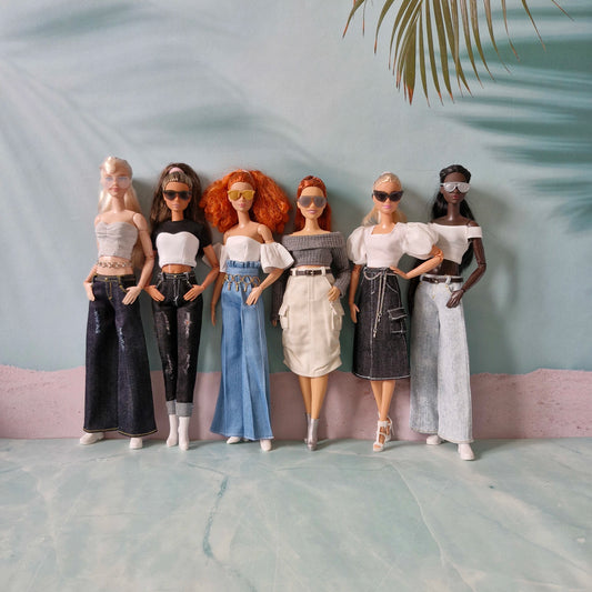 Five dolls with different hairstyles and outfits standing against a light gray background.