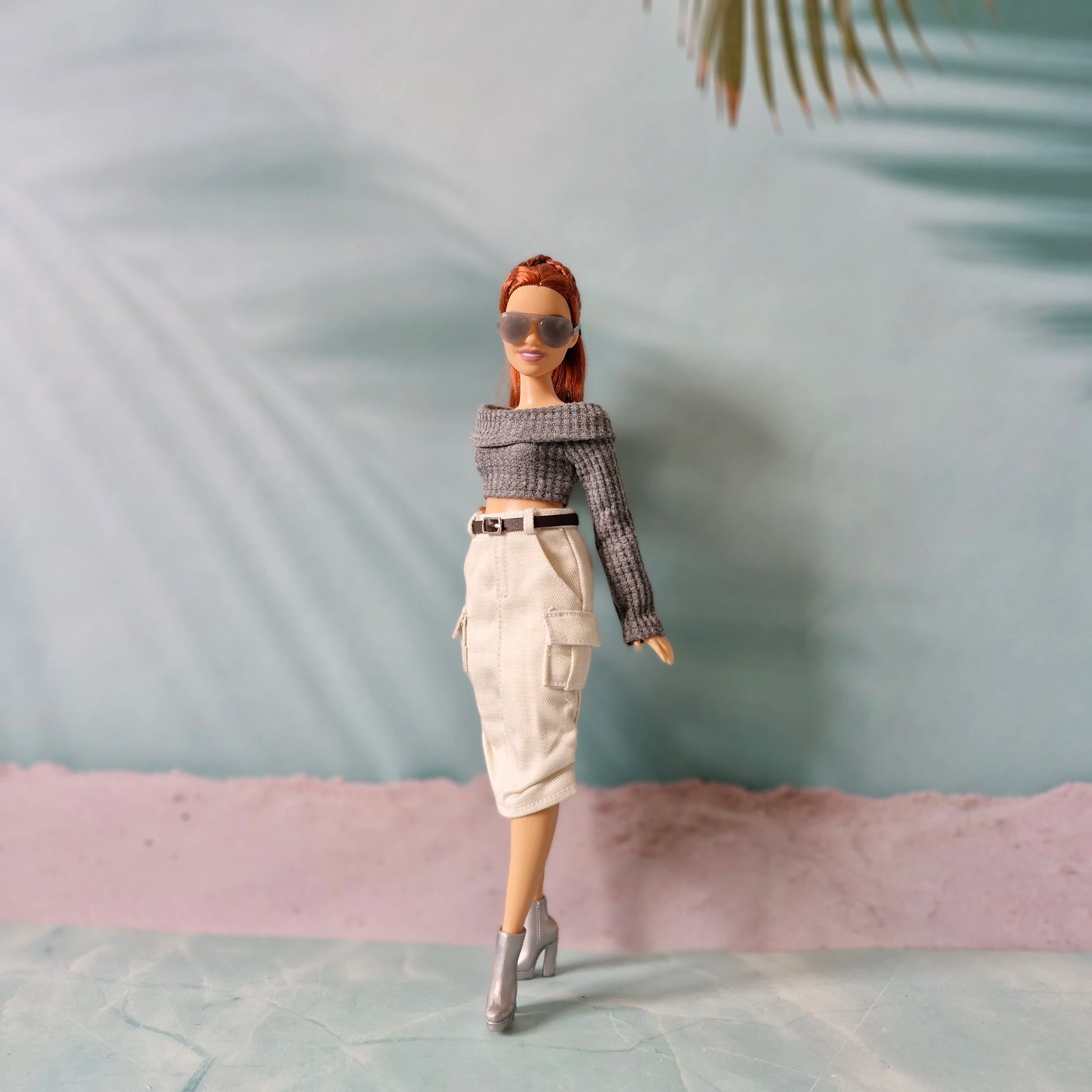 Fashion doll wearing sunglasses and a outfit with a blurred background