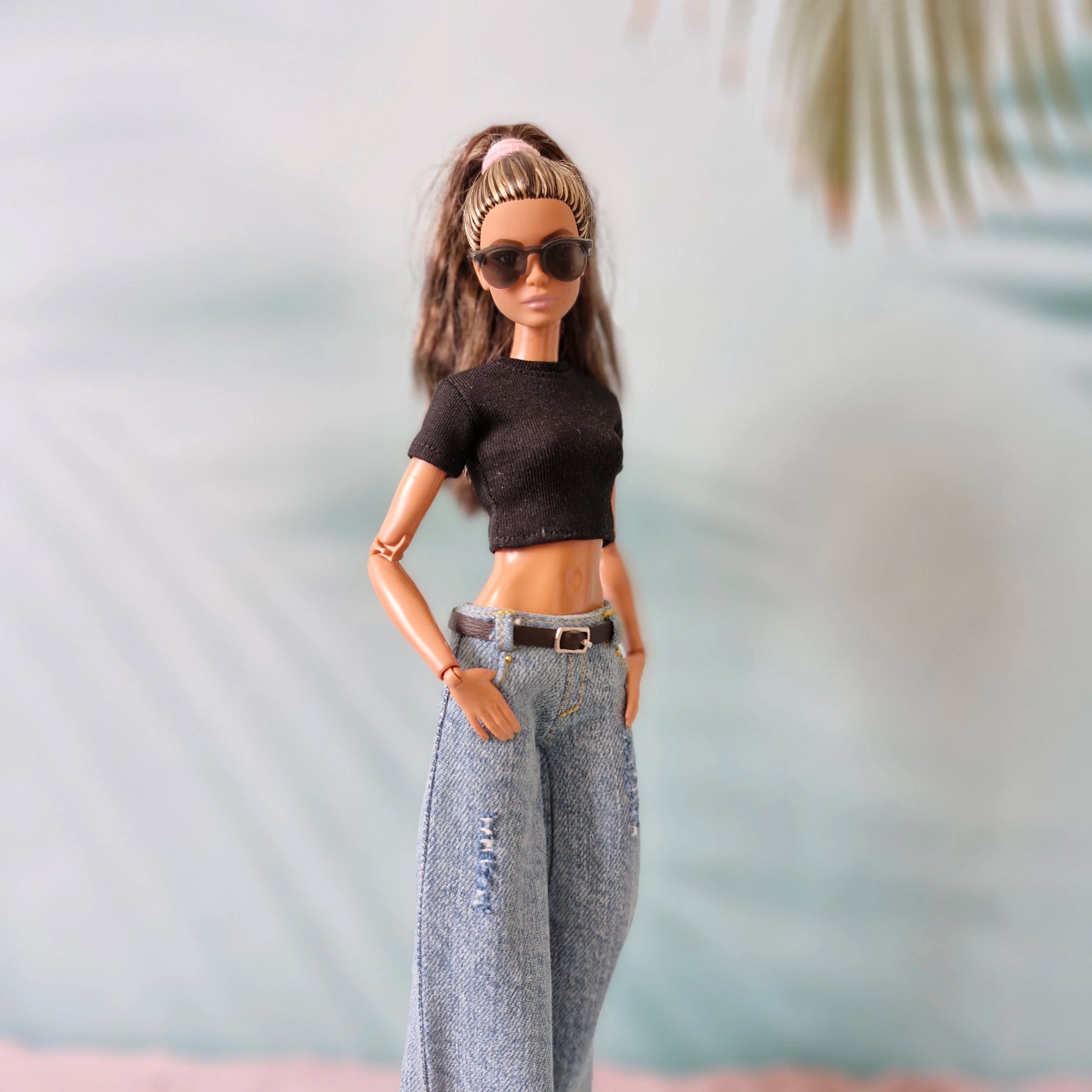 Barbie doll wearing a black crop top and blue jeans with a blurred background