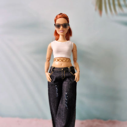 Doll with red hair wearing sunglasses, a white top, and black jeans against a neutral background