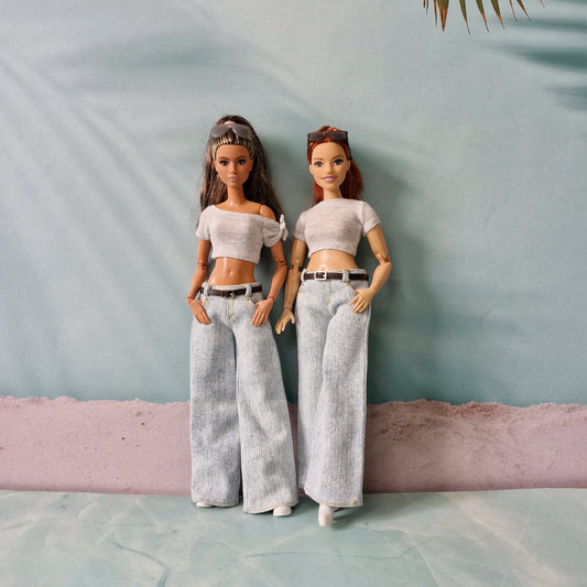 Two dolls wearing matching outfits against a plain background