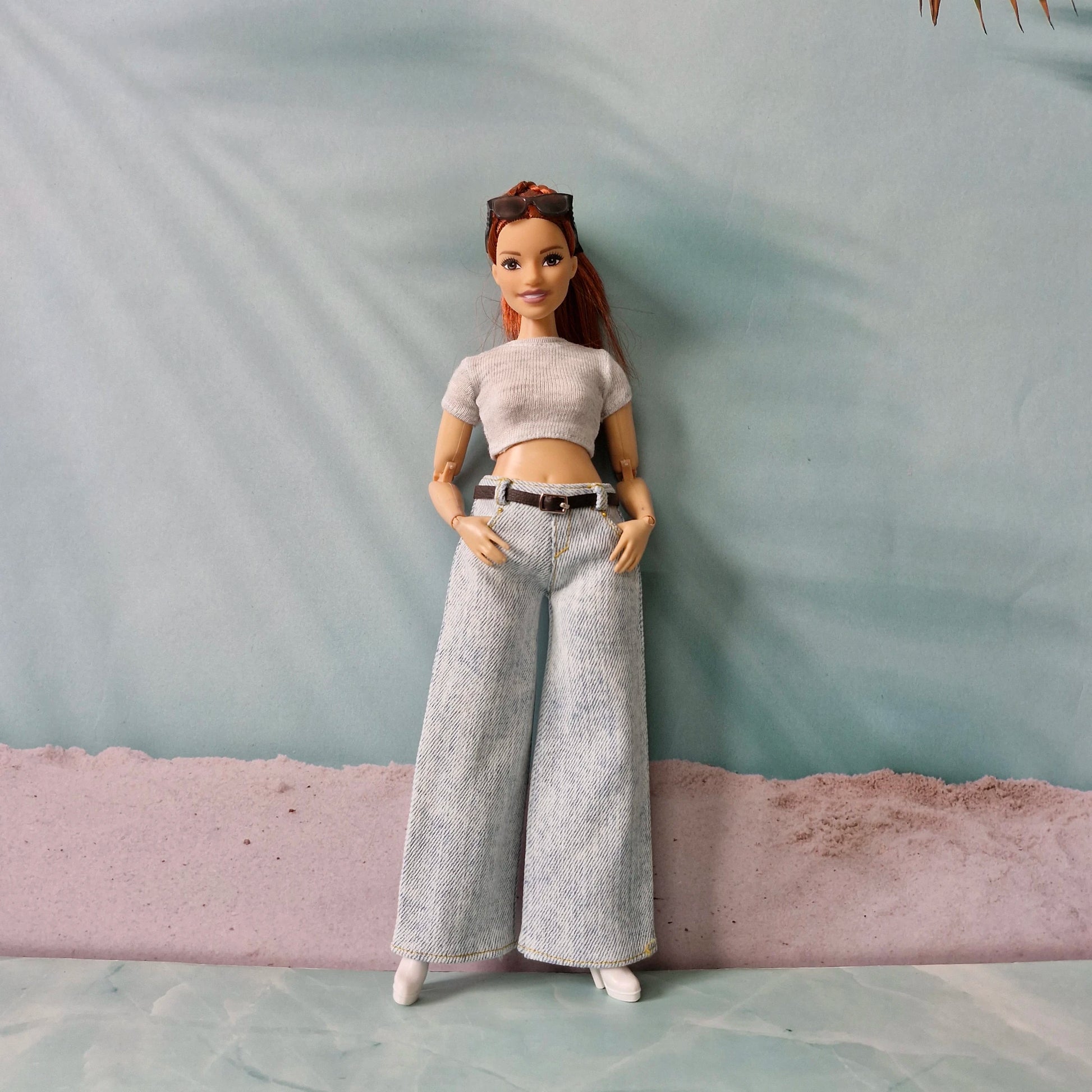 Barbie doll wearing a light gray top and wide-leg jeans against a plain background