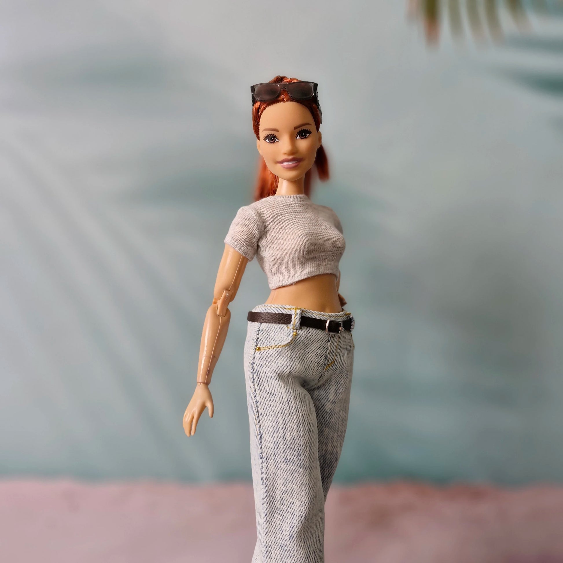 Barbie doll with red hair and casual outfit against a blurred background