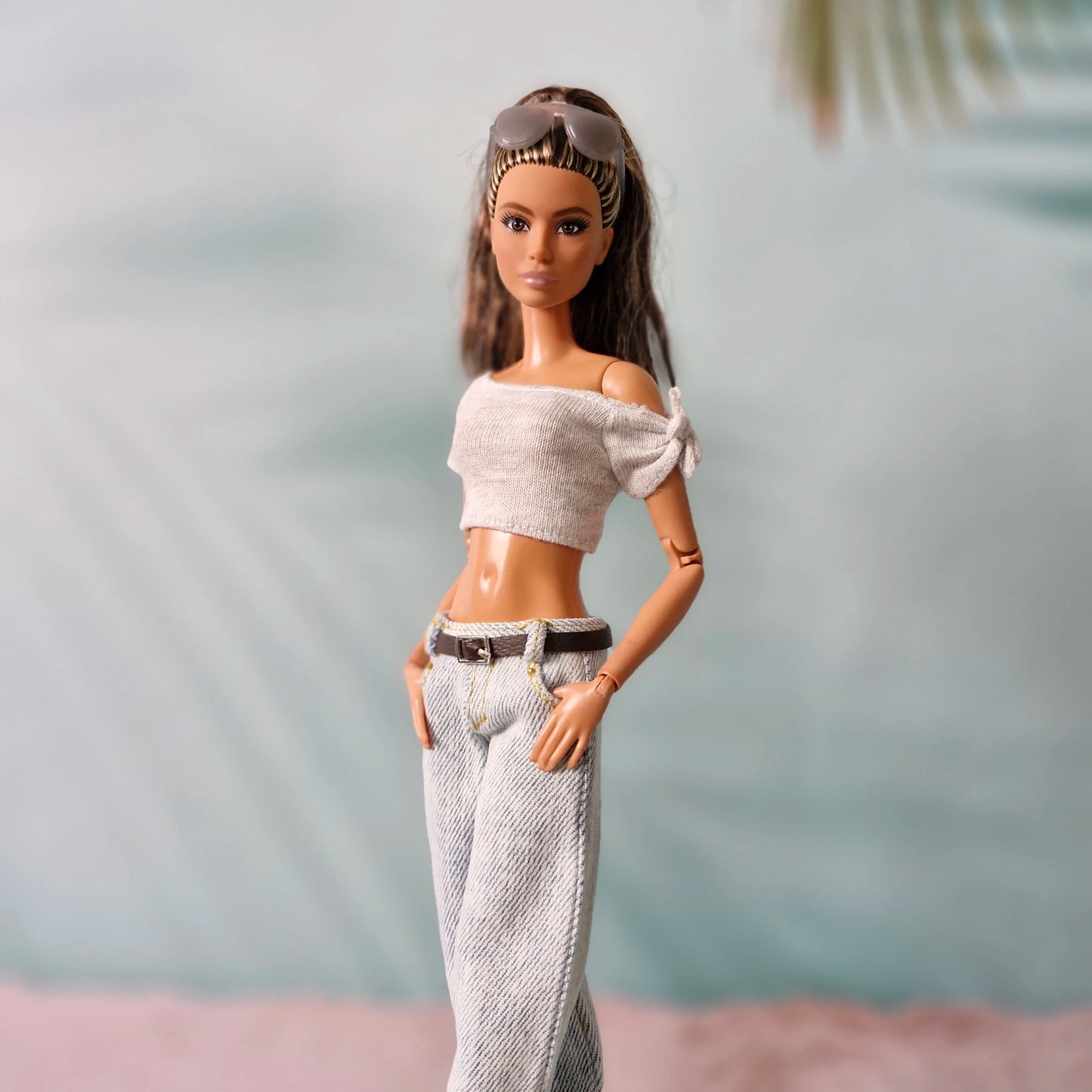 Barbie doll wearing a white off-shoulder top and patterned pants with a blurred background